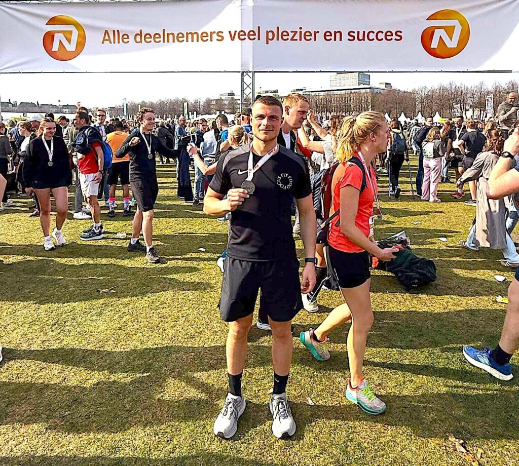 F3 Fysio therapeut houdt zijn medaille omhoog na de NN Rotterdam Marathon