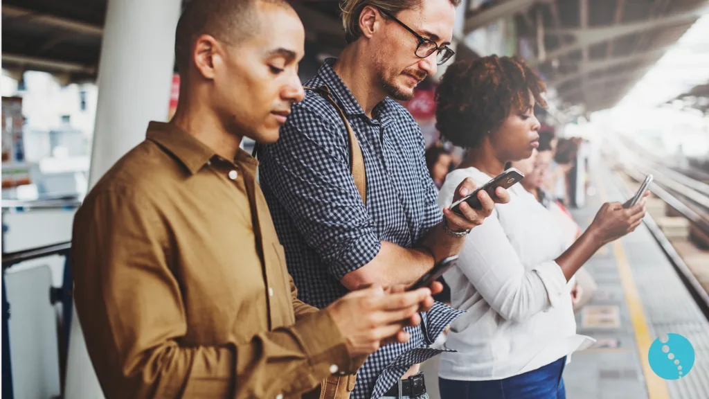 Mensen kijken langdurig op hun telefoon op het perron – verhoogd risico op technek en nekklachten.