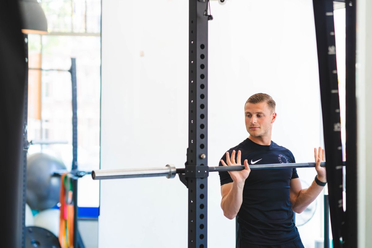 Man traint in oefenruimte van F3 Fysio en past een halterstang aan. Dit zijn kracht- en spieroefeningen.