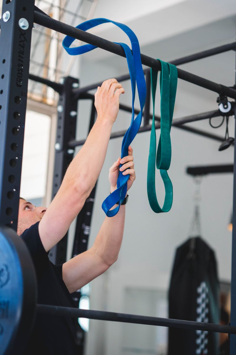 Persoon traint met weerstandsbanden in de fysio, gericht op spierversterking en fitnessoefeningen, goed uitgeruste fysio.