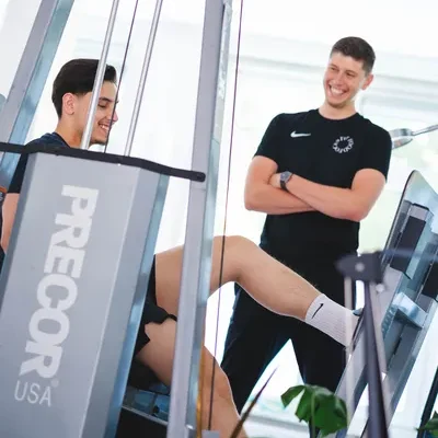 Man doet legpress oefening in een lichte fitnessruimte onder begeleiding van de F3 fysiotherapeut voor knieklachten