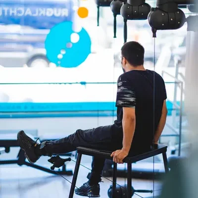 Man zit op een verhoging en doet knie oefening in moderne fitnessruimte van F3 fysio op de walenburgerweg te Rotterdam