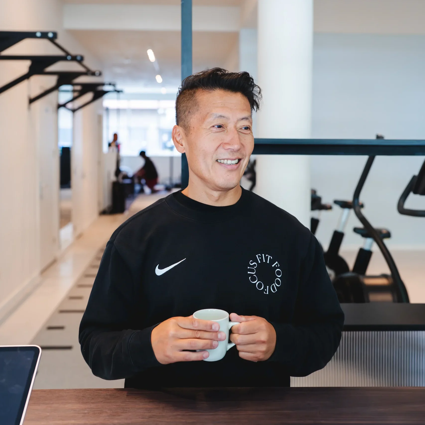 Fysiotherapeut staat met kop koffie bij de balie van F3 fysio te Rotterdam