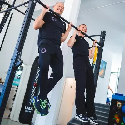 F3 fysiotherapeuten trekken zich op aan een stang in een lichte en moderne fitnessruimte