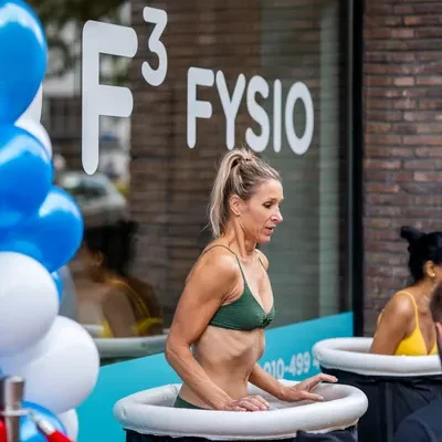 Vrouw stapt in ijsbad voor de deur van de nieuwe vestiging van F3 Fysio op de Mariniersweg te Rotterdam