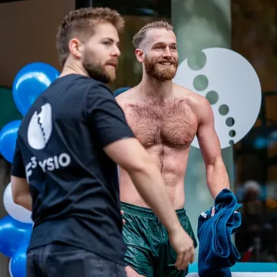Sportieve man in zwembroek die net in een ijsbad is geweest staat met handdoek bij de F3 Fyio ijsbadmeester