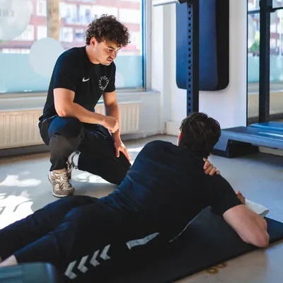 Man ligt op yogamat en doet oefening tegen schouderklachten onder begeleiding van de F3 fysiotherapeut