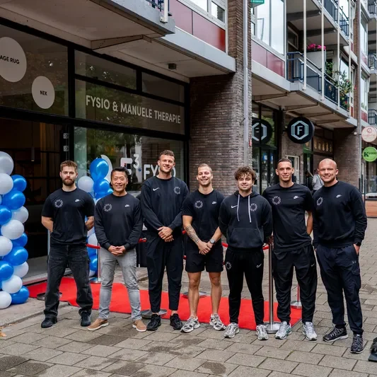 Teamfoto van alle F3 fysiotherapeuten voor de deur van de nieuwe vestiging op de Mariniersweg te Rotterdam