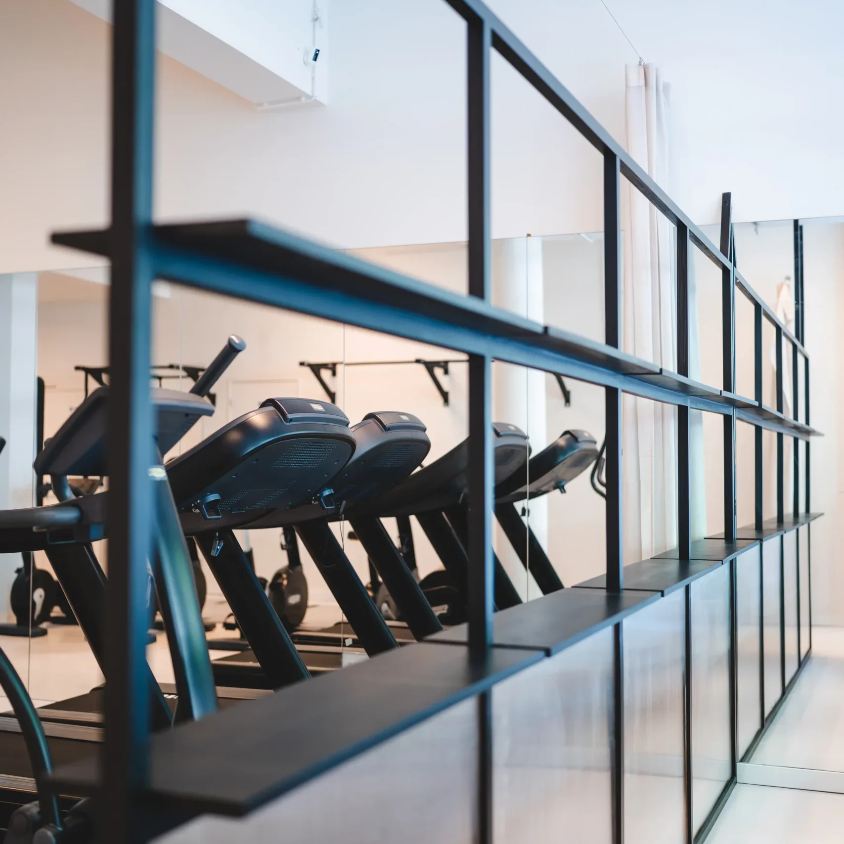 Meerdere hometrainers op een rij in een moderne en lichte fitnessruimte bij F3 Fysio.
