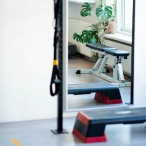 Lichte fitnessruimte met plant, trainingsbankje en weerstandsbanden