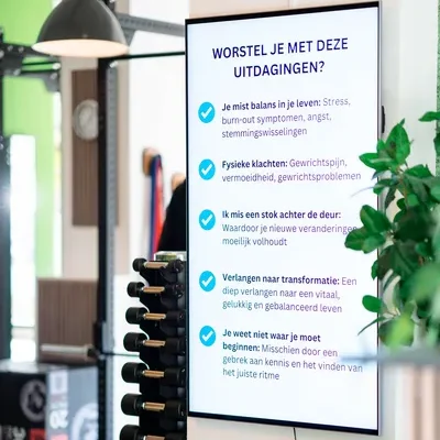 Trainingsruimte met digitaal bord waarop gevraagd wordt of je worstelt met de uitdagingen als missen van balans