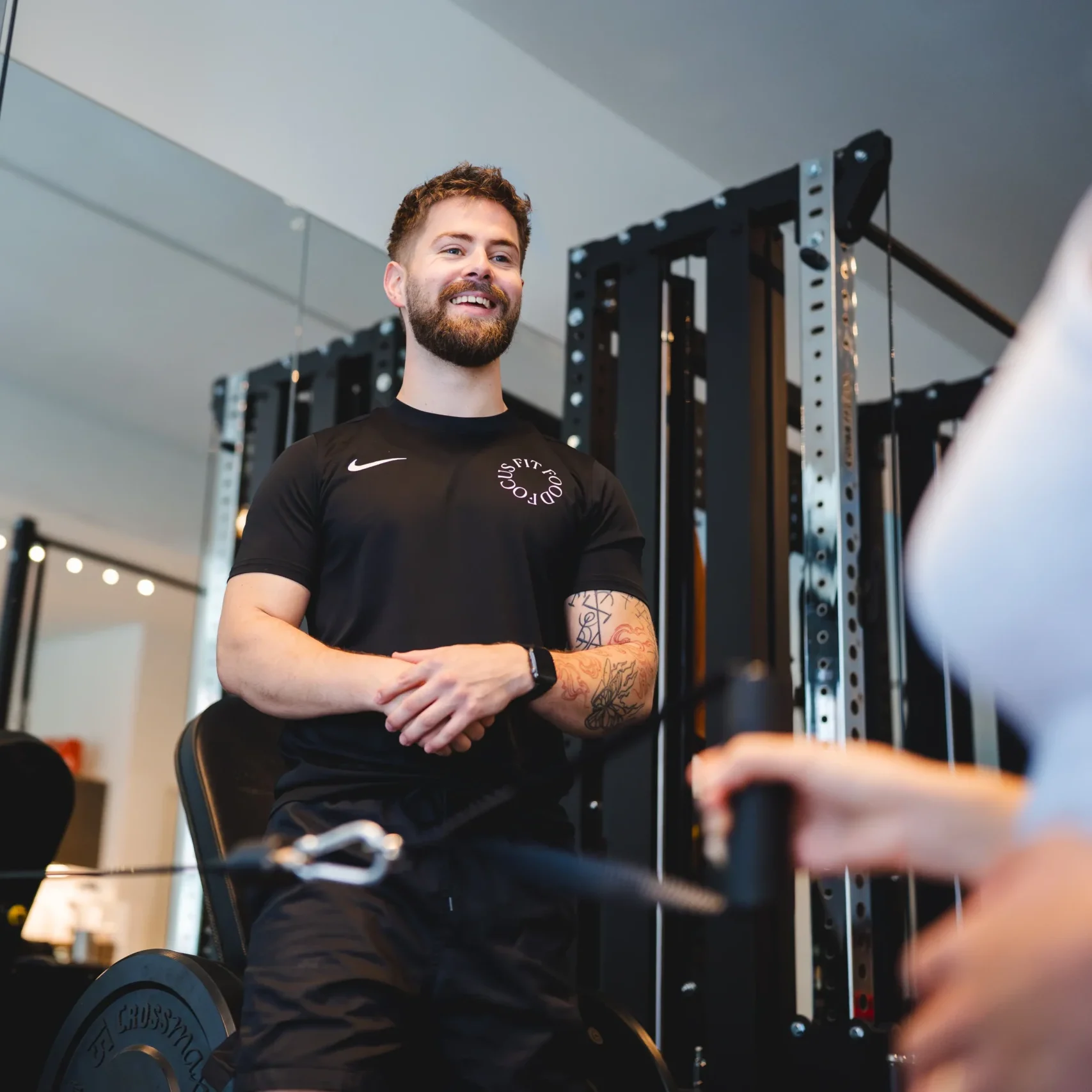 Fysiotherapeut begeleid zwangere vrouw met een schouderoefening in een moderne fitnessruimte.
