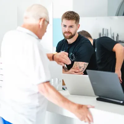 F3 fysiotherapeut maakt afspraak in lichte trainingsruimte met client