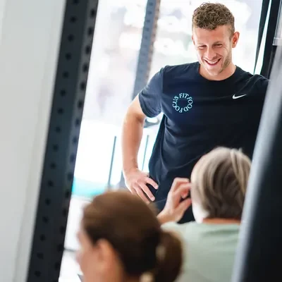 Lachende F3 fysiotherapeut staat bij client in moderne en lichte trainingsruimte