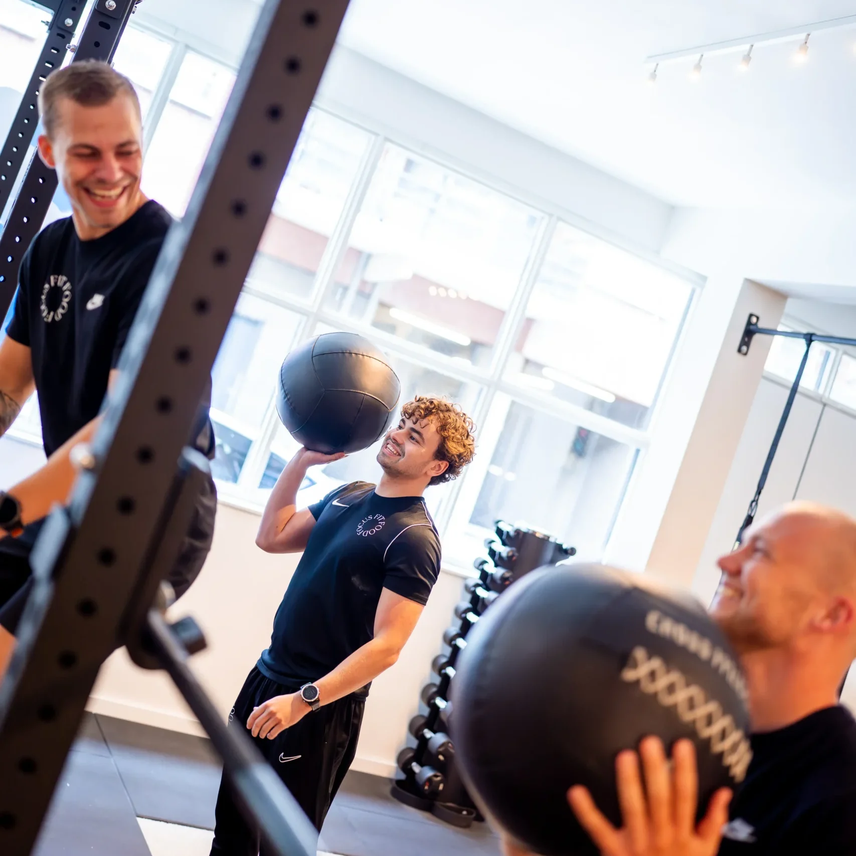 Drie fysiotherapeuten met medicijnballen in de praktijk.
